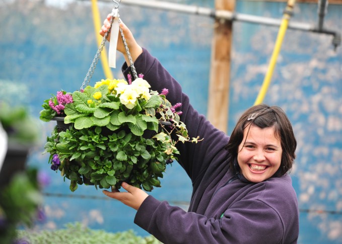 Girl holding hanging basket of flowers