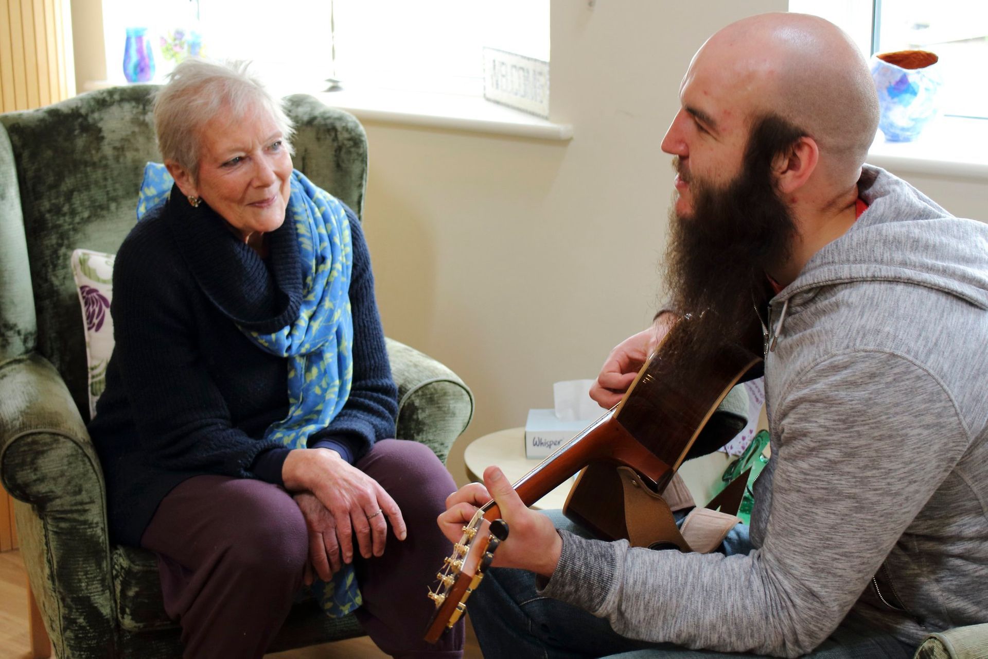Man playing guitar to older woman