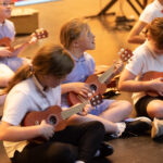 Children seated paying the guitar