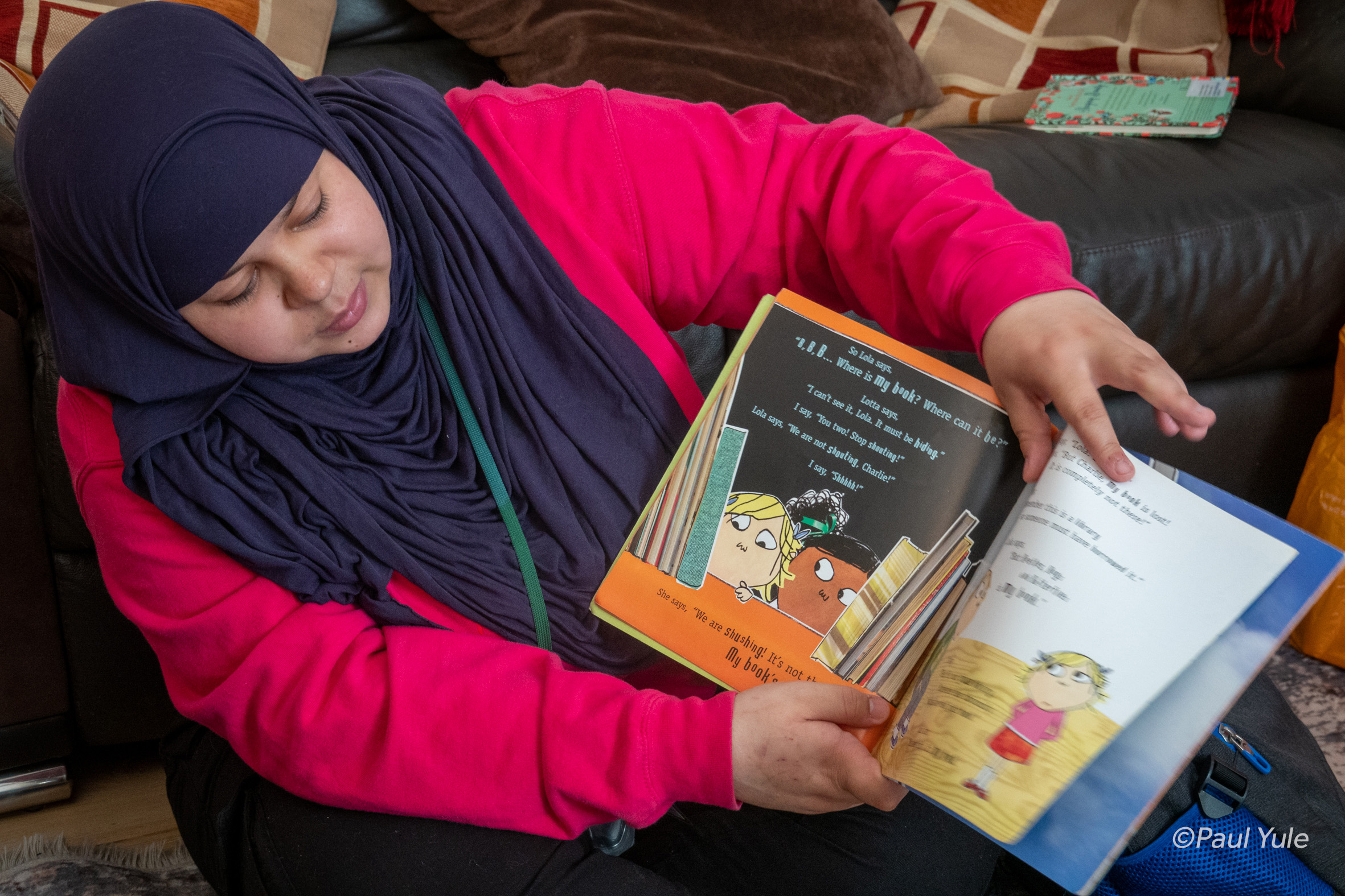 Lady in head scarf reading book to child
